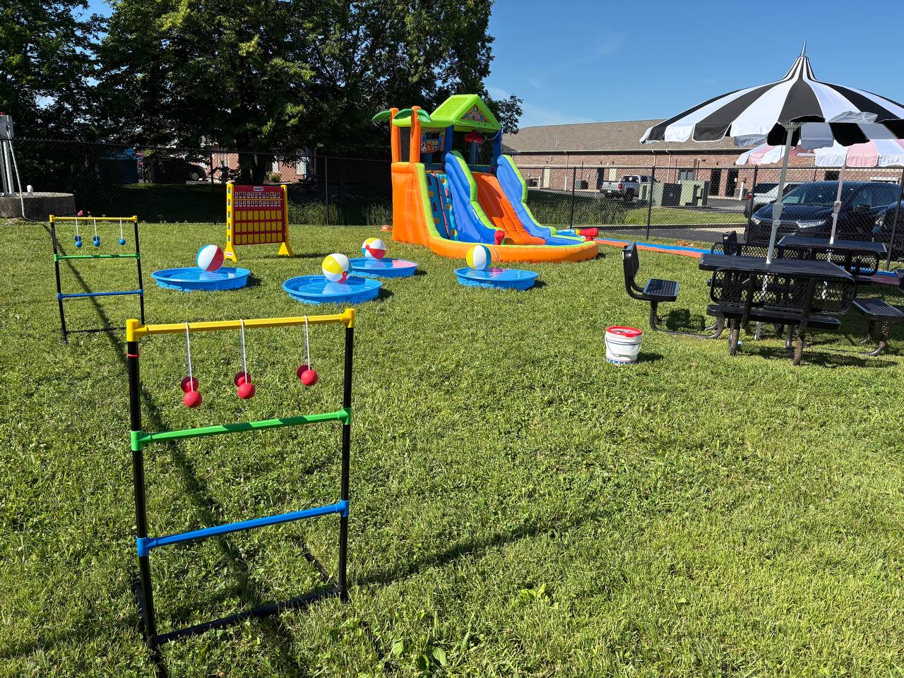 Large outdoor party setup with inflatable slide, yard games, and water activities