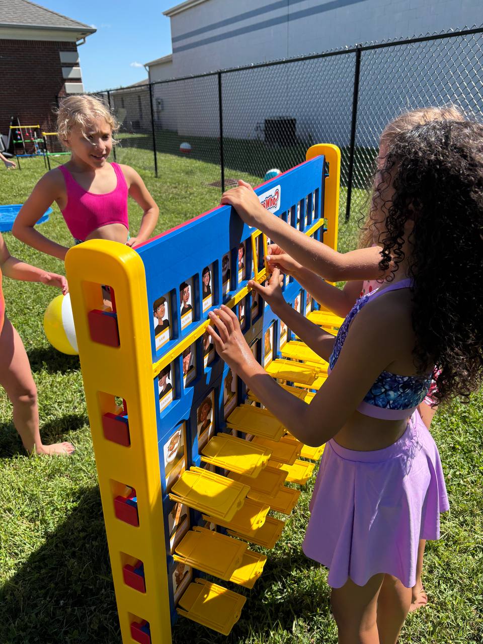 Large outdoor party setup with inflatable slide, yard games, and water activities